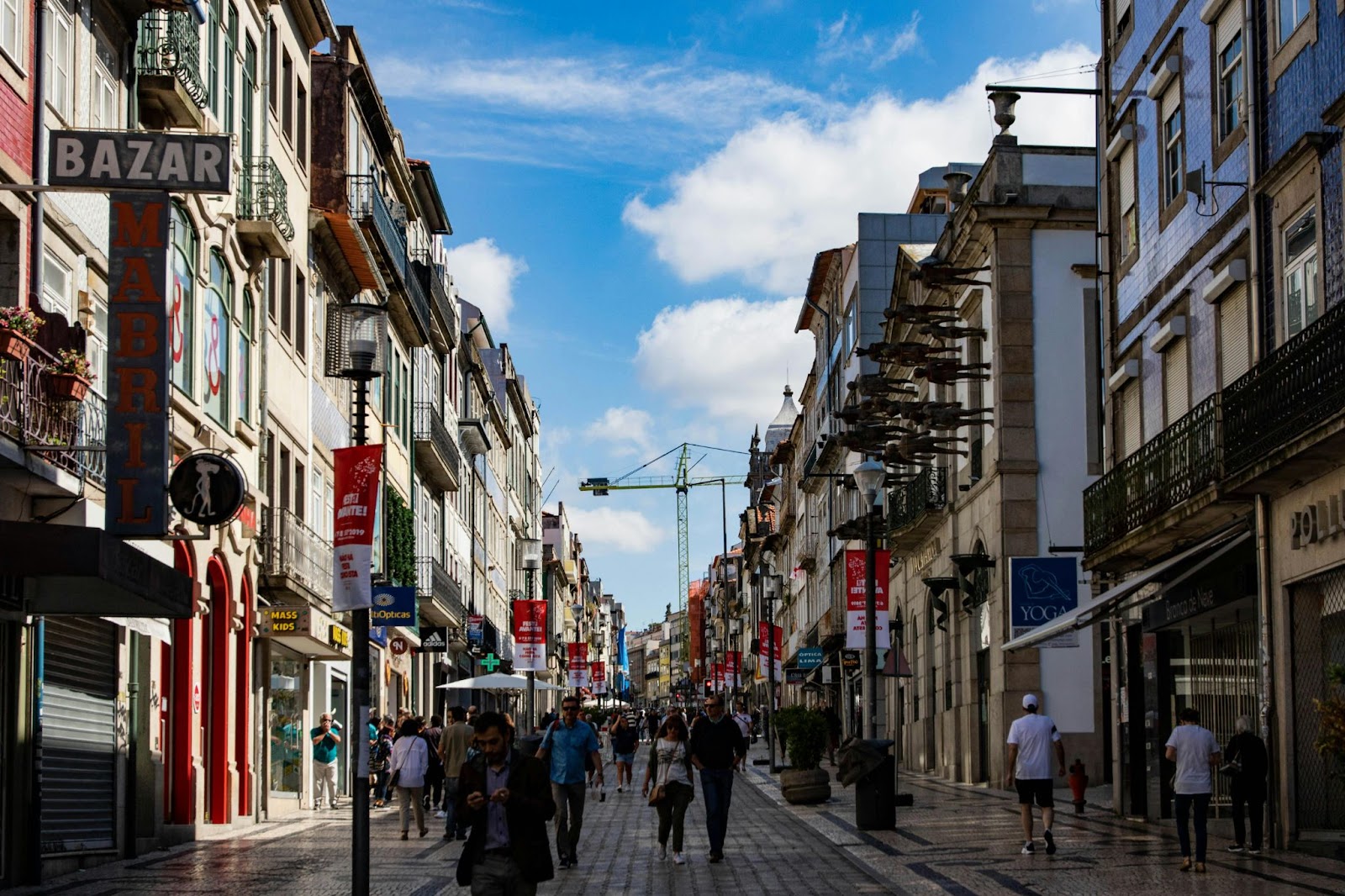Busy pedestrian street lined with shops and historic buildings in Porto.